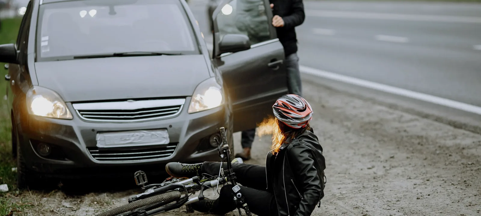 Ciclista caída ao lado de um carro após atropelamento