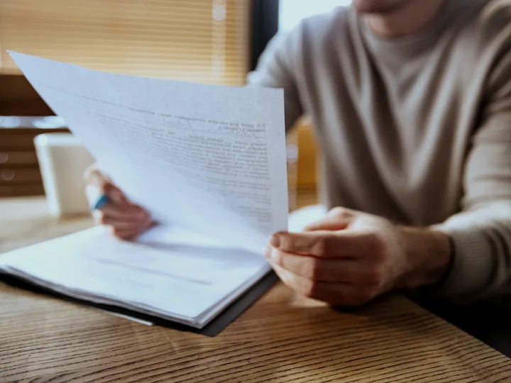 Homem sentado à mesa analisa um documento
